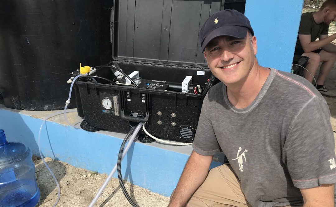 World Hope International CEO John Lyon with a state of the art machine that can transform sea water into fresh, drinkable water.