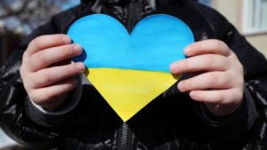 Child holding Ukrainian color heart shape
