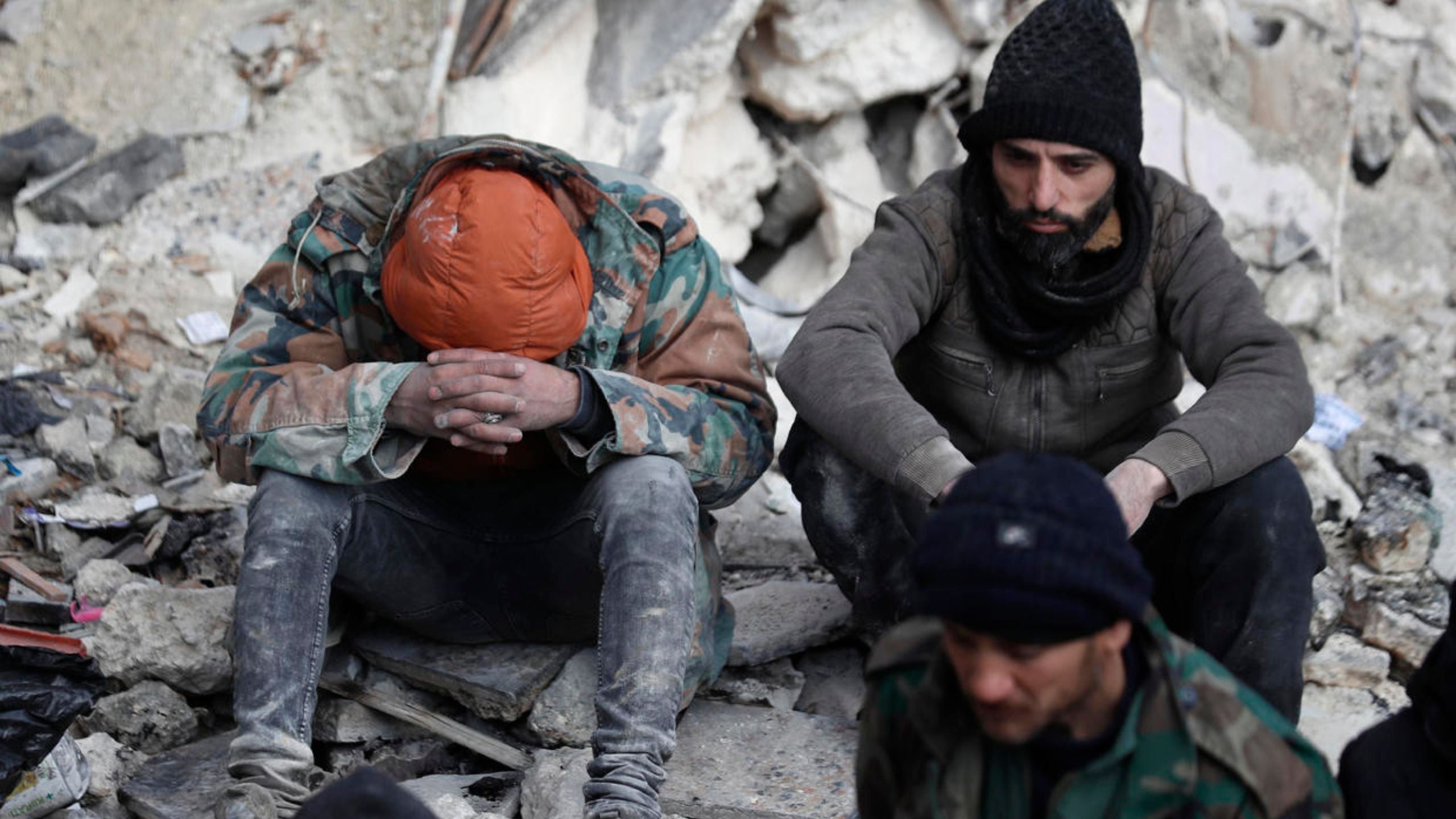 2 Earthquake survivors sitting in rubble