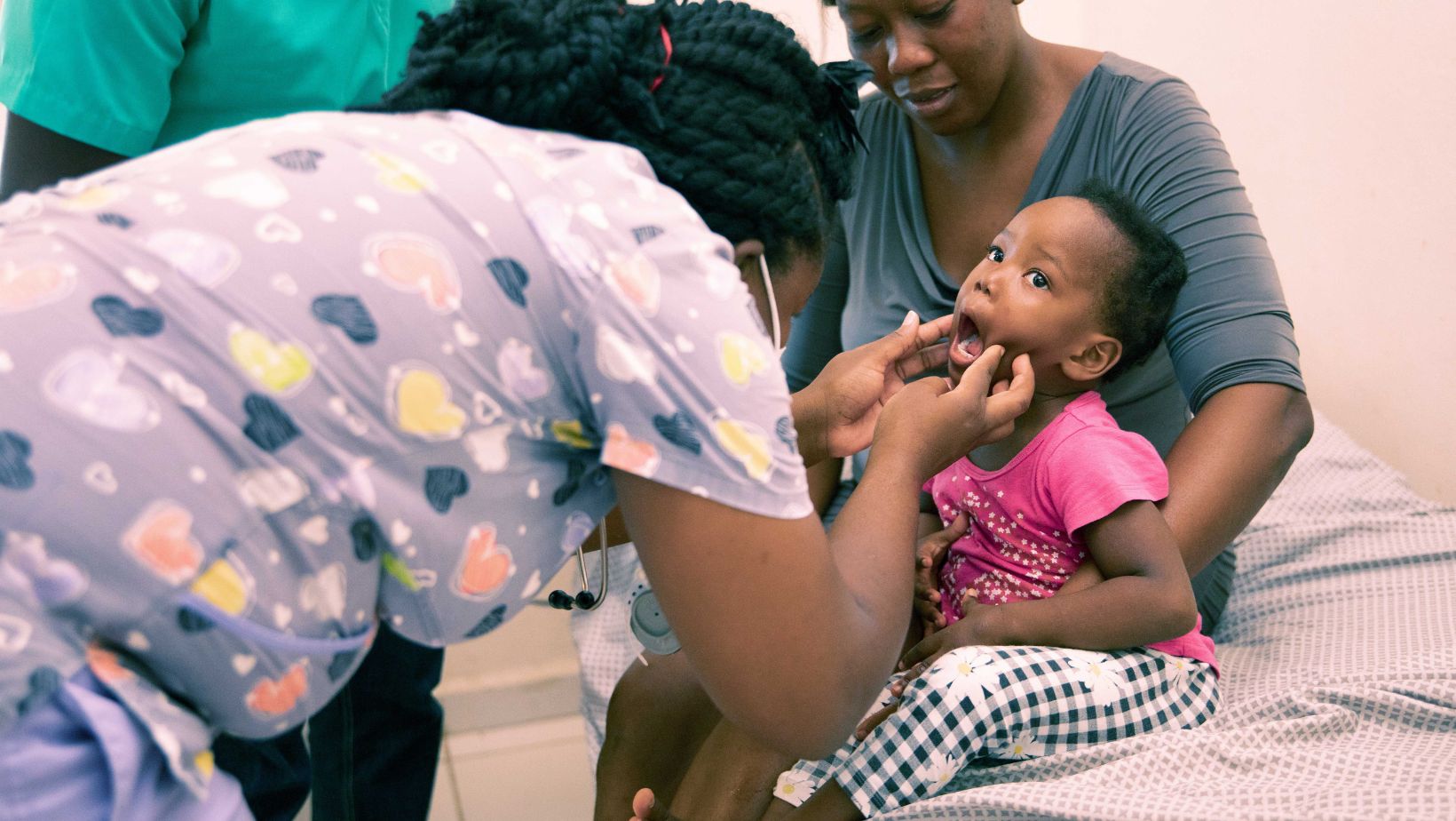 Doctor/Nurse examining a young patient while her mom holds her