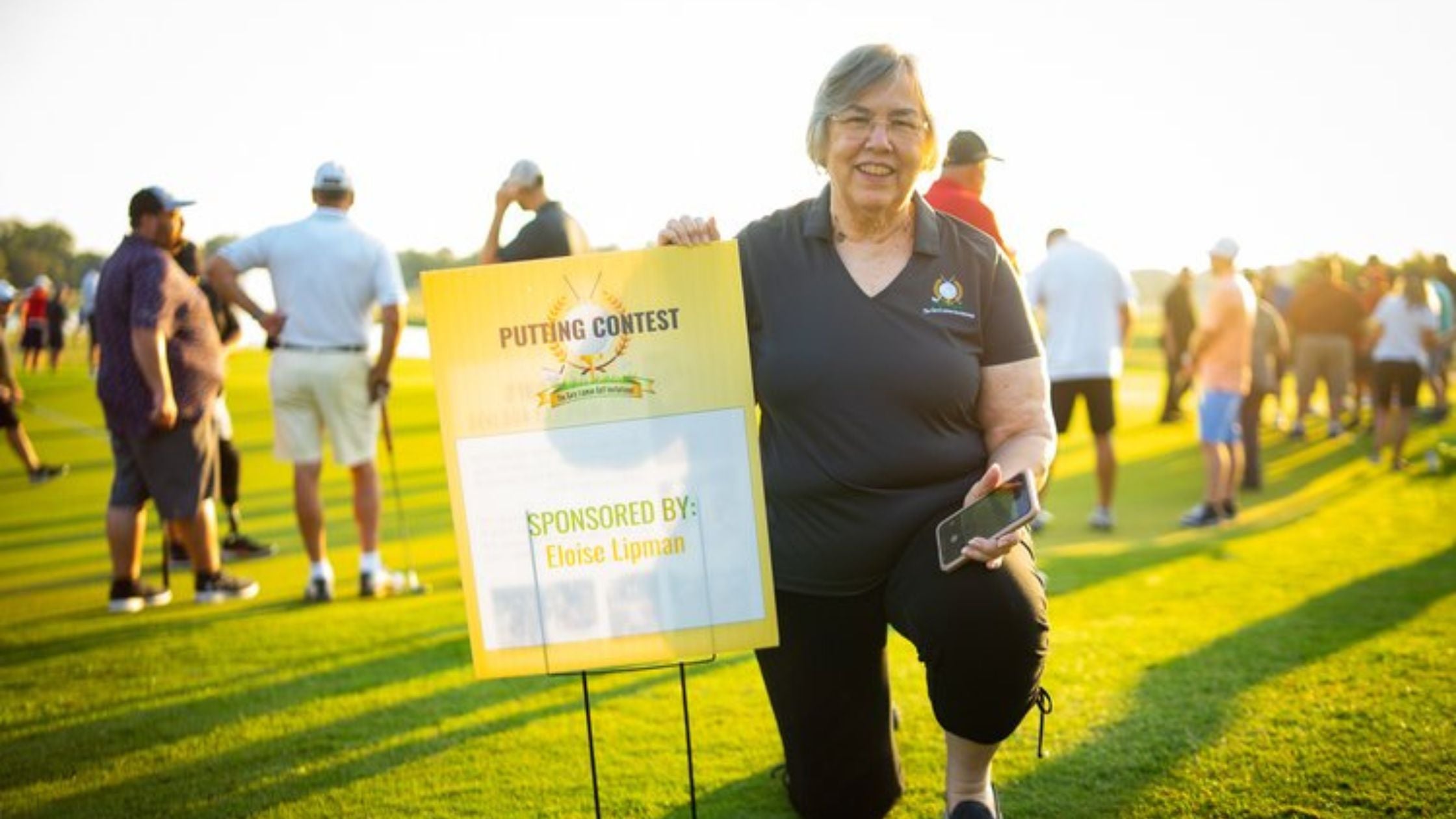 Eloisee Lipman holding up a sponsorship sign at the golf tournament