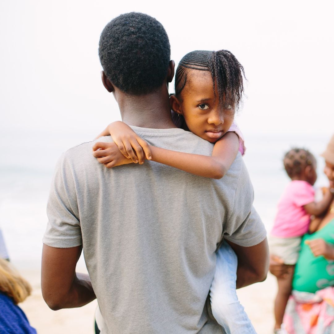 Father carrying his daughter on the beach in Sierra Leone