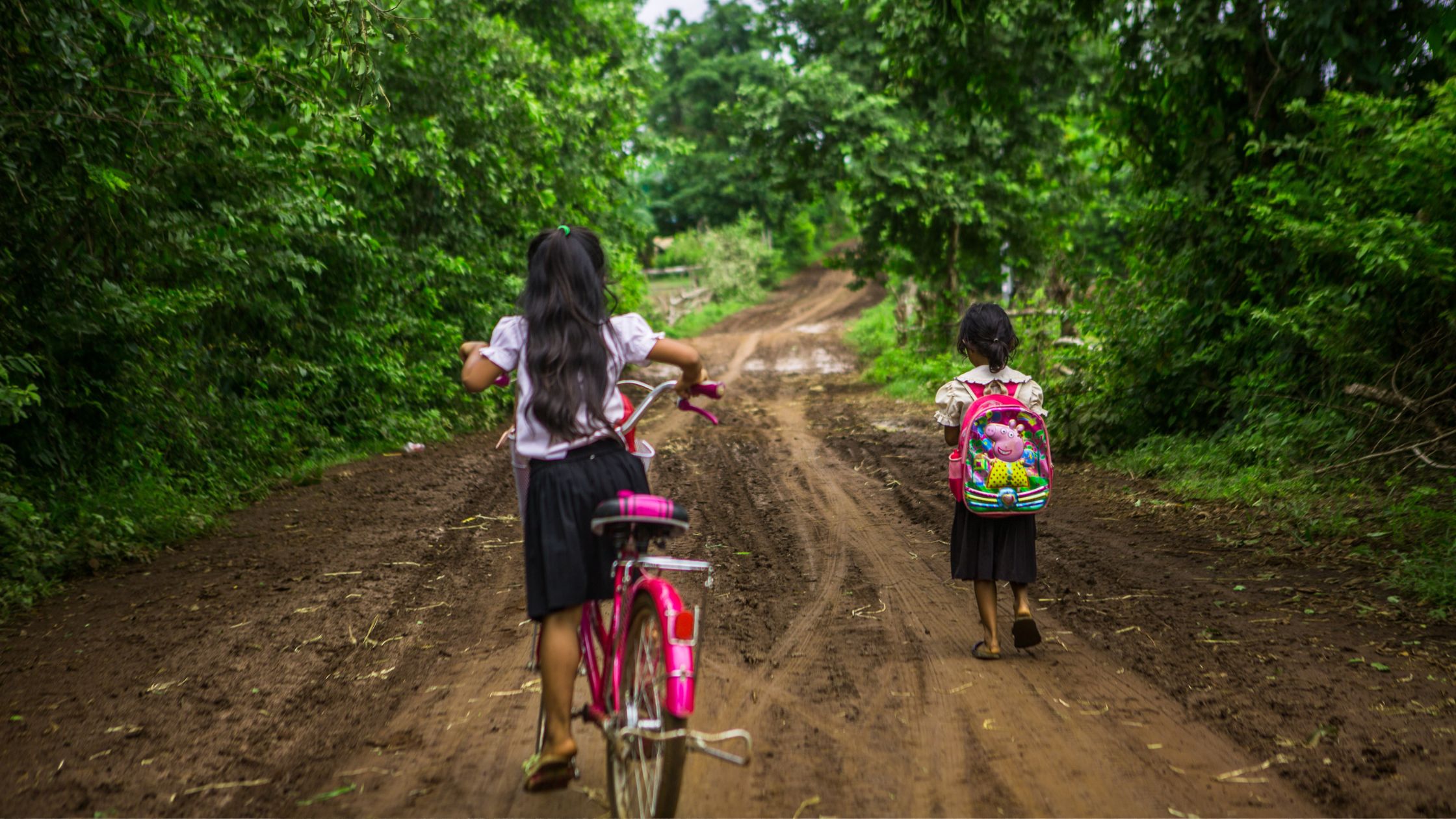 Girls going to school on bike & foot in the Philippines
