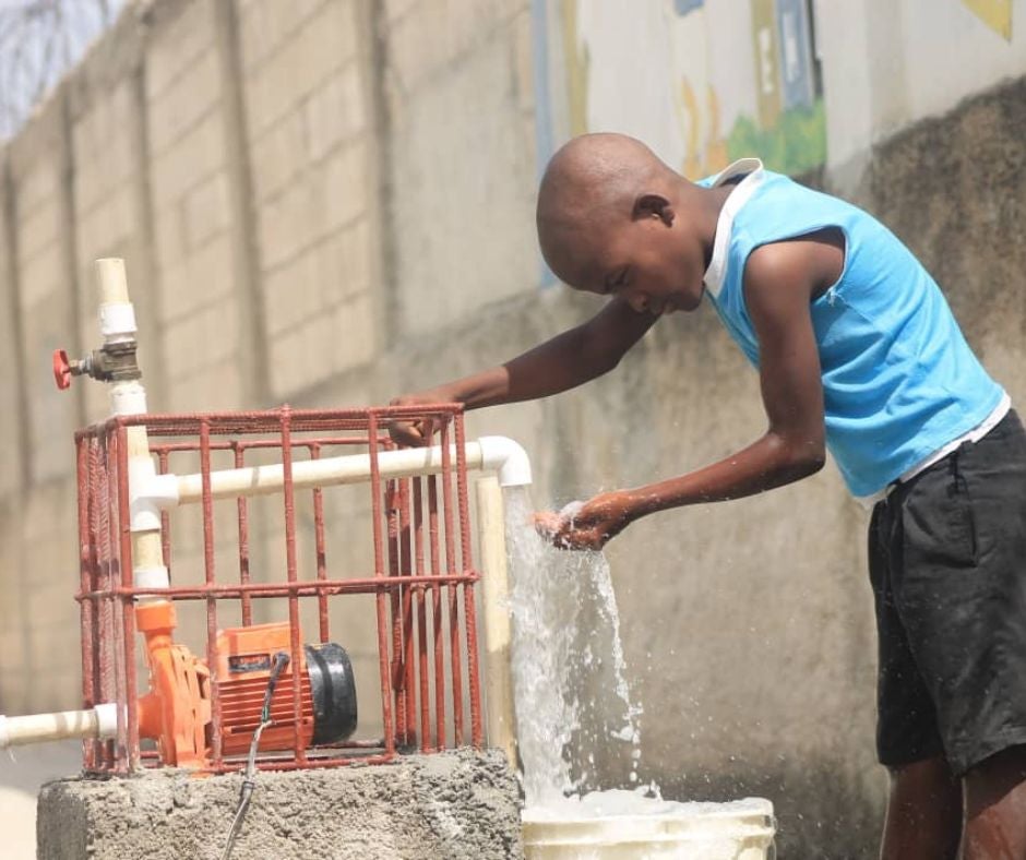 young boy filling bucket with clean water in Haiti