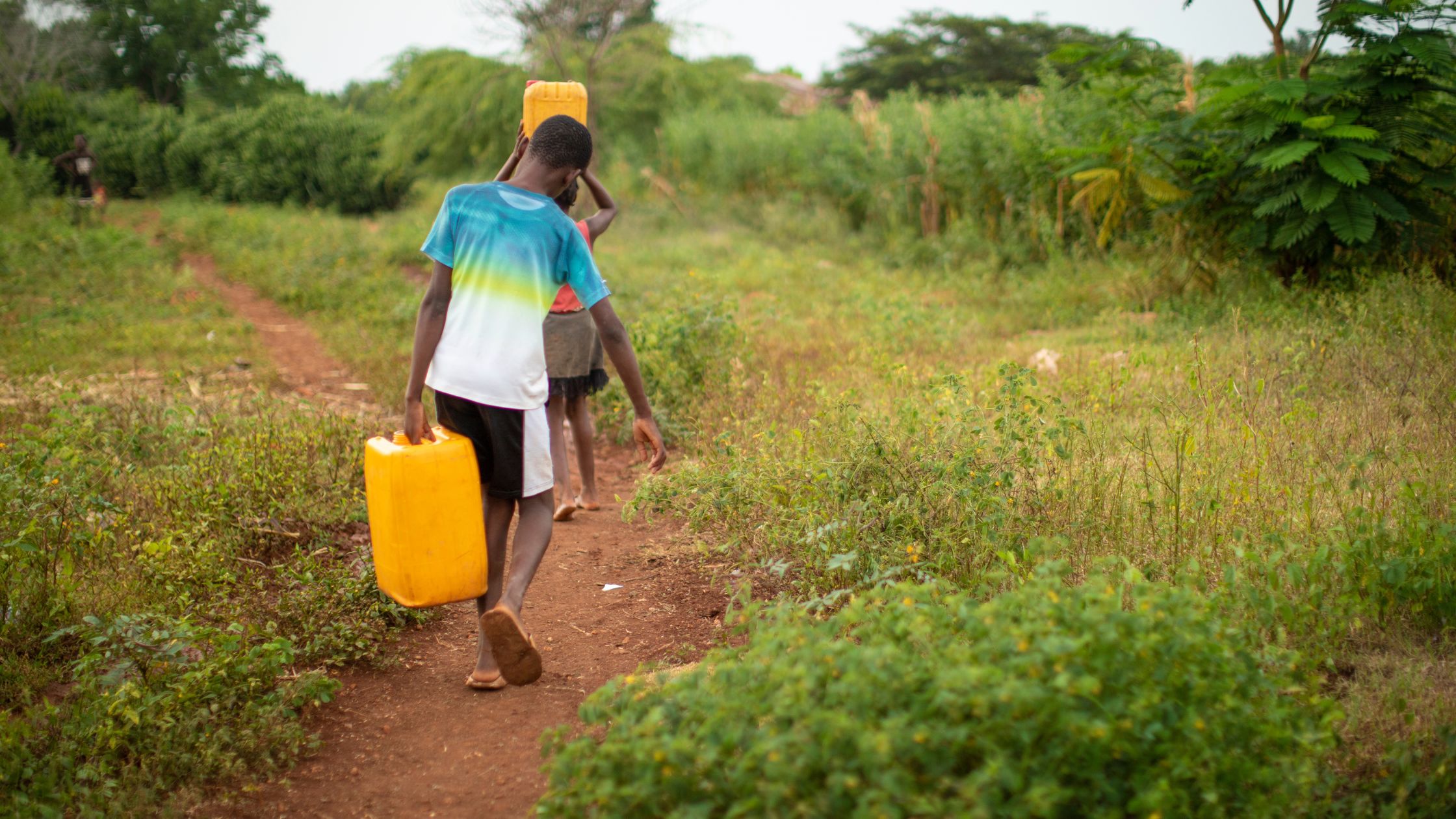 boys walking with yellow water jugs in Haiti.