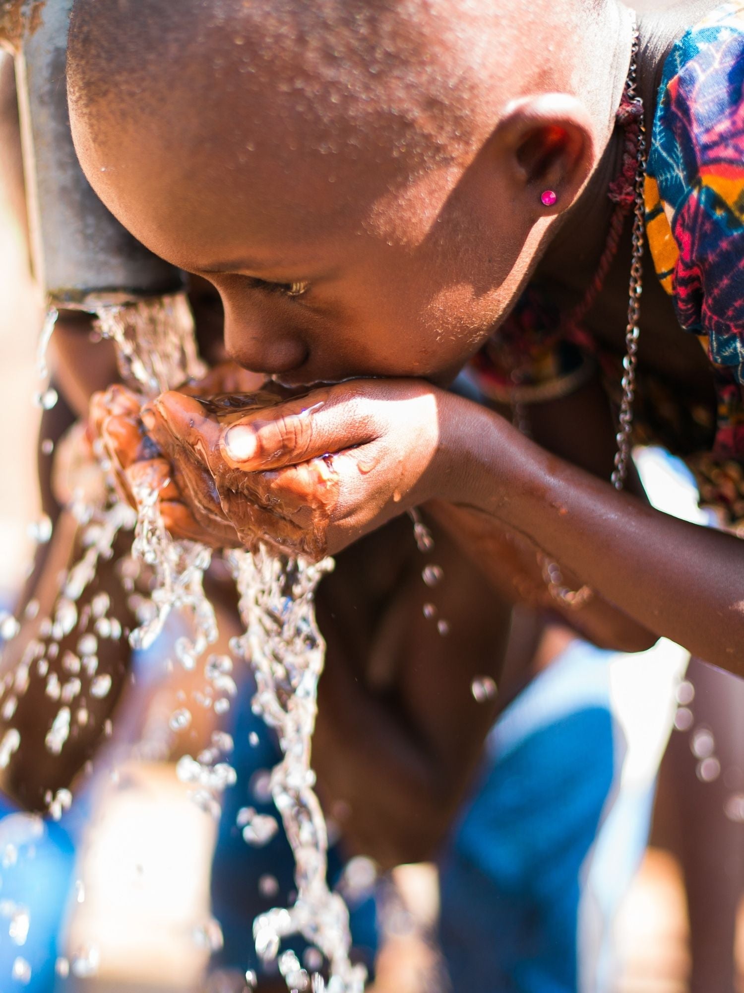 Child drinking water from water pump.
